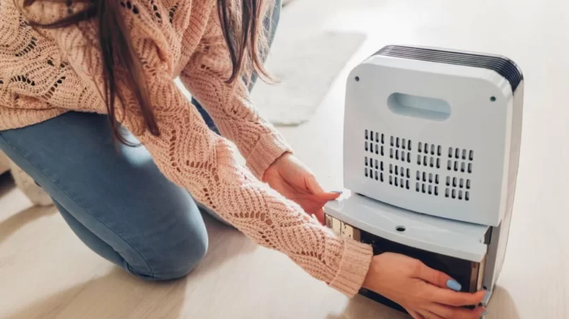 Woman changing water container of dehumidifier