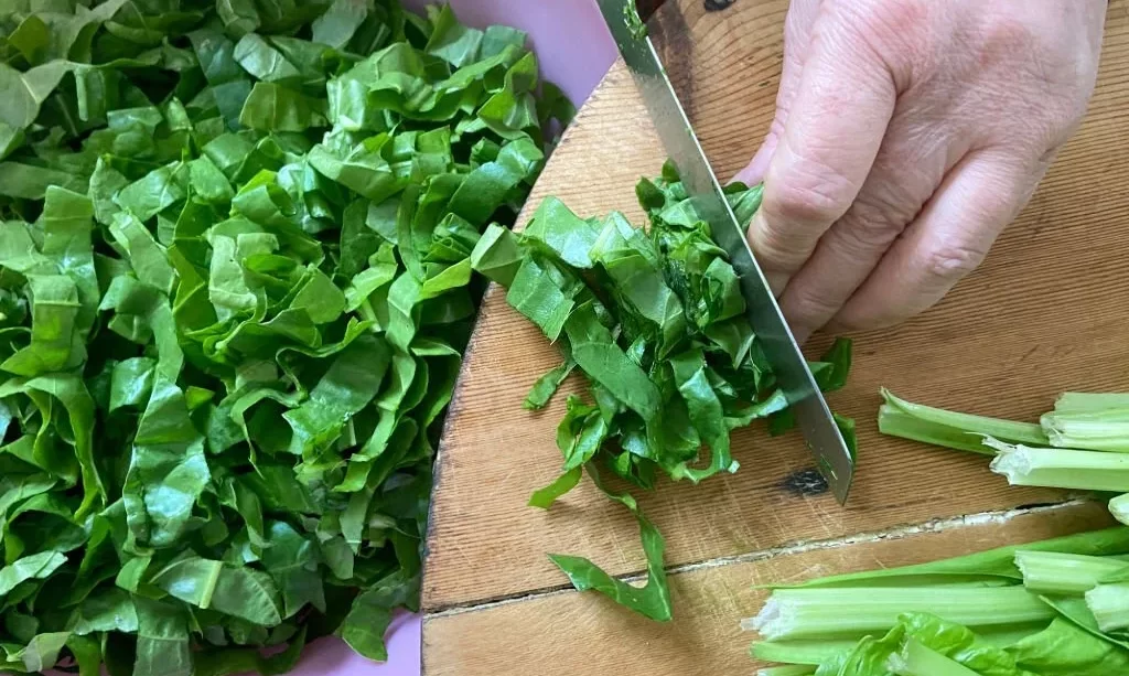 hand chopping fresh chards on the cutting board