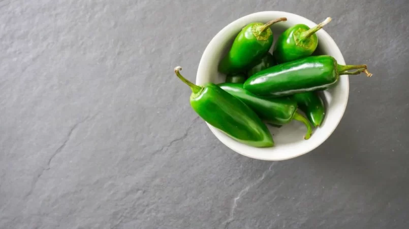 A white bowl filled with bright green jalapeno peppers