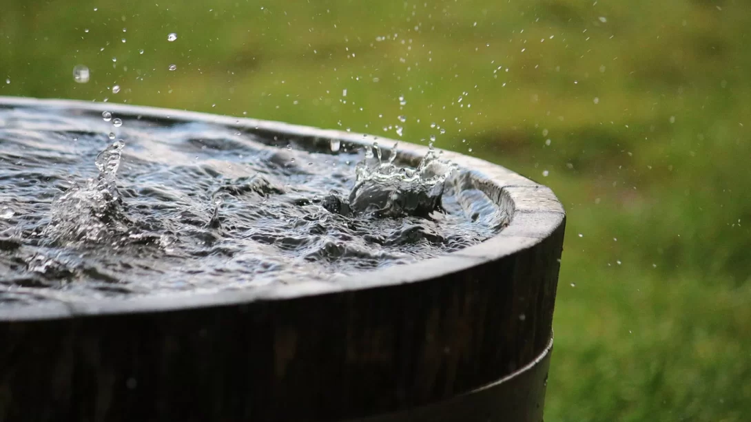 Rain is falling in a wooden barrel full of water in the garden